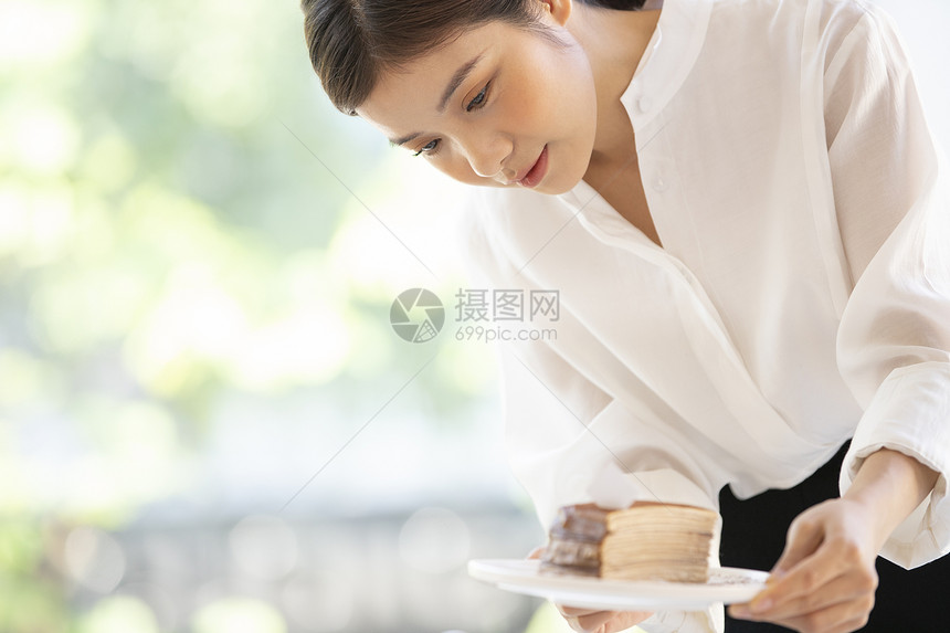 年轻女子端着精致小蛋糕图片