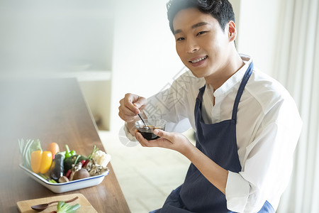 调制酱料的青年厨师图片