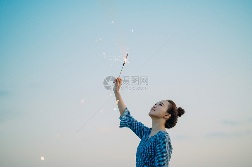 海边放烟花的年轻女子图片