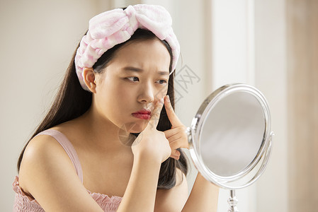 年轻女性照化妆镜子挤脸上的痘痘图片