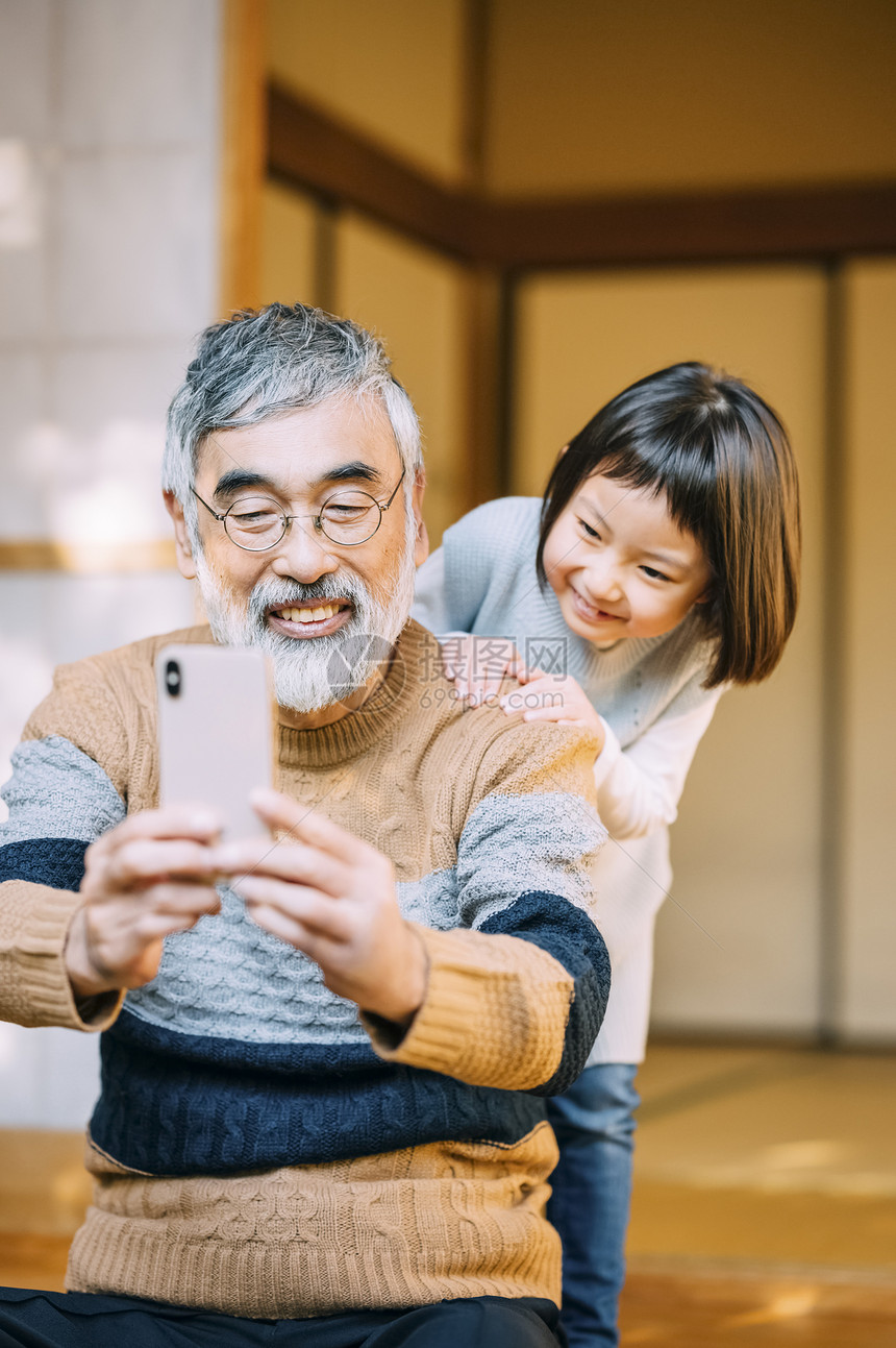 爷爷和孙女使用智能手机拍照图片