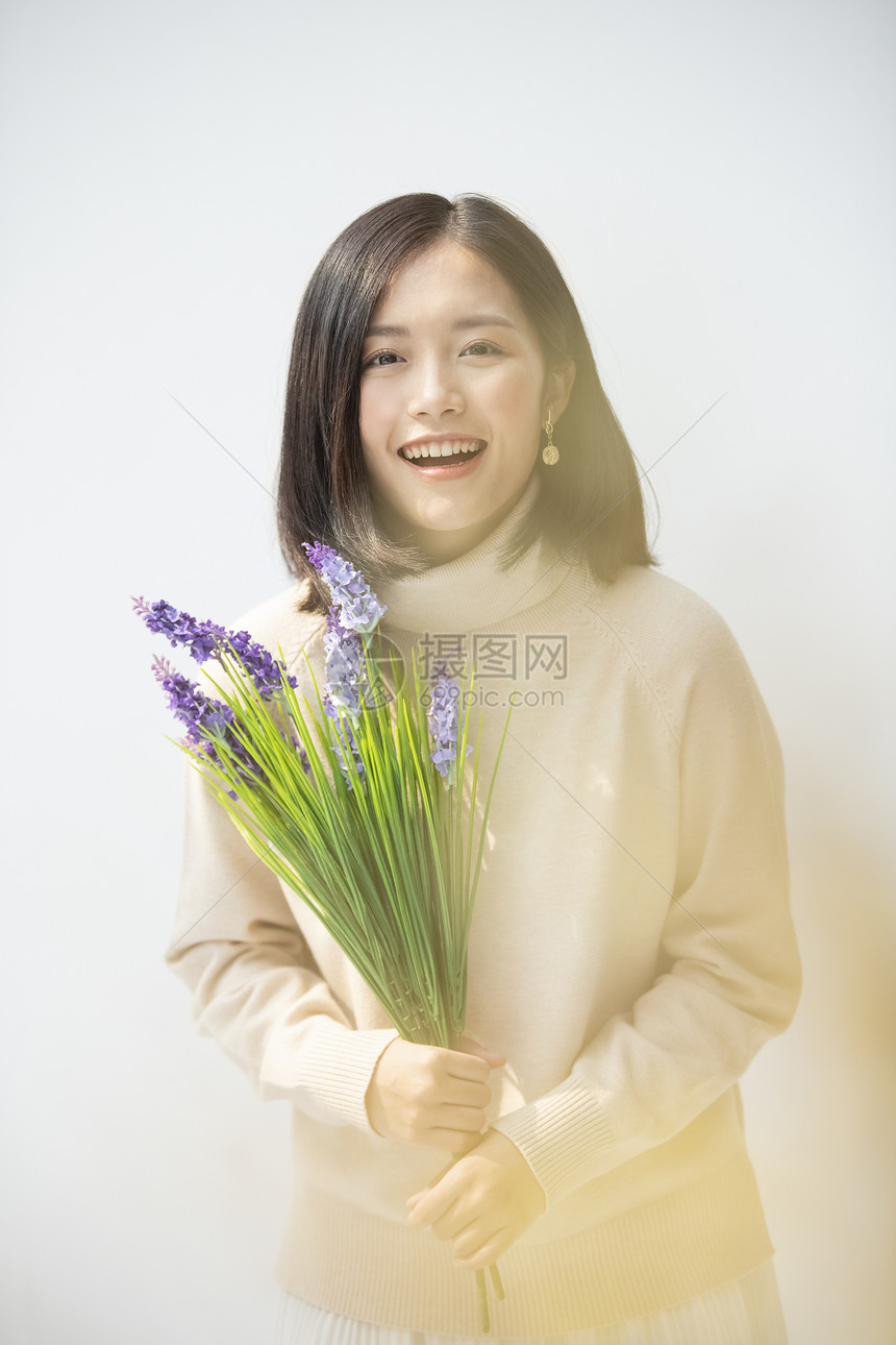 休闲留白掌握手捧花的年轻女子的画像图片