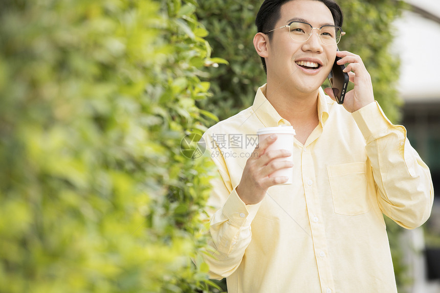 一个戴眼镜的男性在户外打电话图片