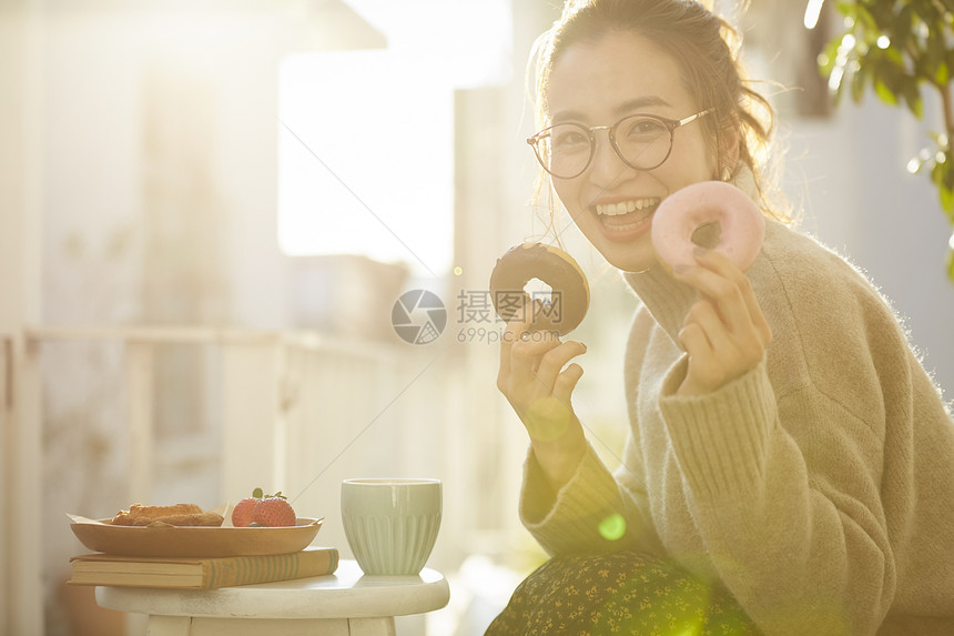 拿着甜甜圈开心的年轻女子图片