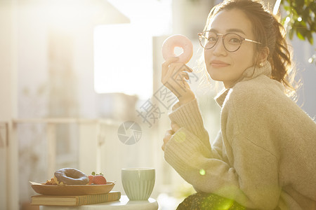 青年女子拿着甜甜圈微笑图片