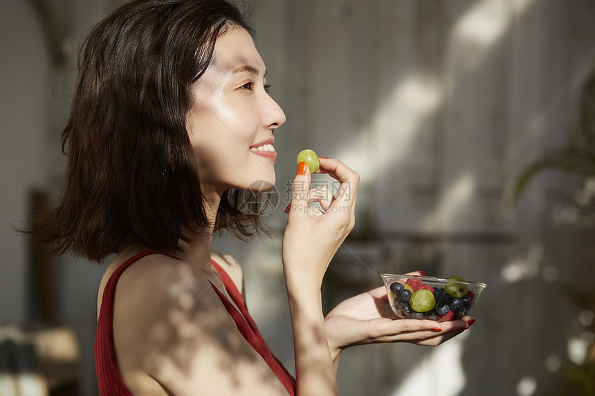 青年女子吃水果微笑图片