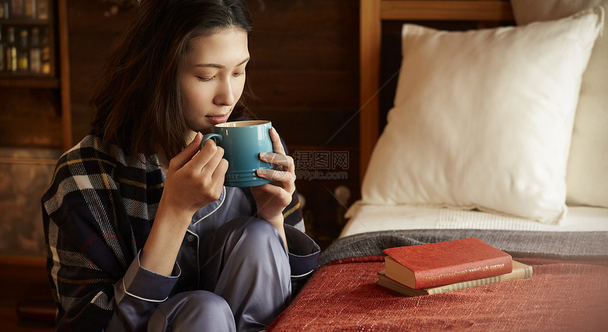 卧室里喝咖啡的年轻女子图片