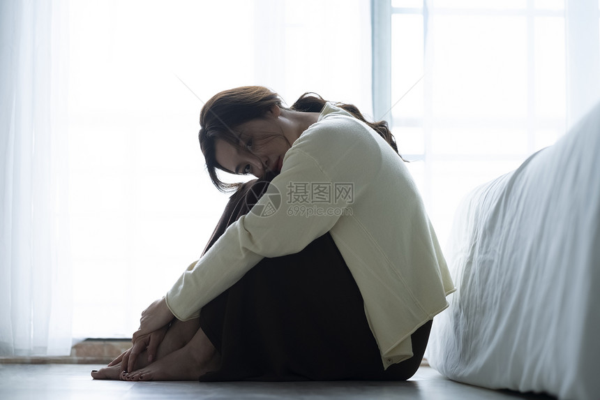情绪低落的年轻女子坐在地板上图片