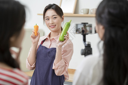 拍摄烹饪做菜短视频的年轻女子背景图片