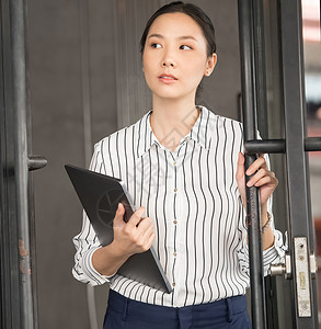 商务女性抱着笔记本电脑推开门白领高清图片素材