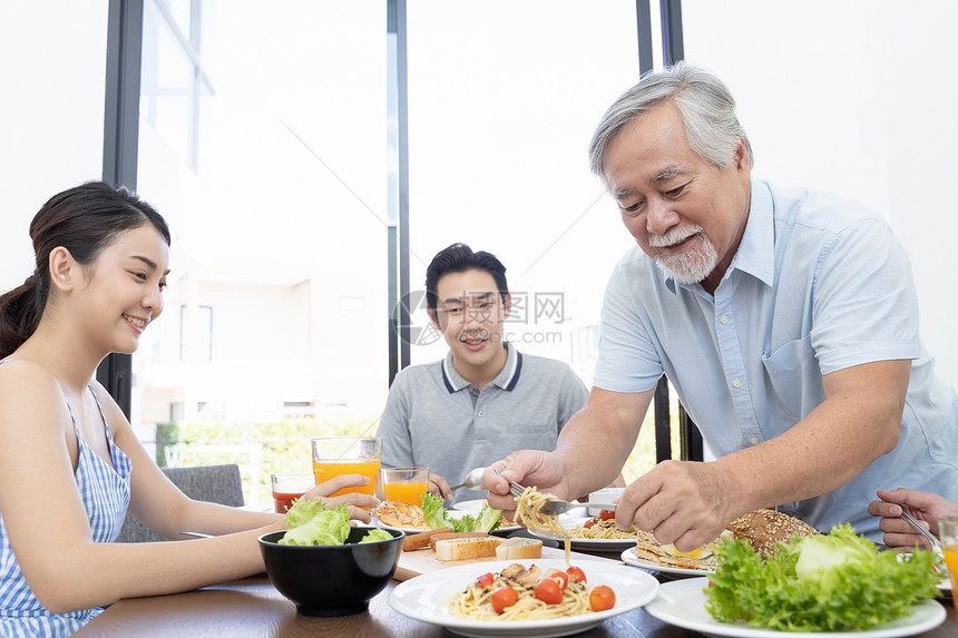 一家人用餐站起身夹菜的祖父图片