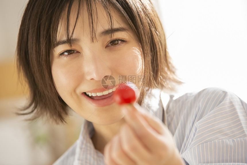 拿着蕃茄微笑的年轻女子图片