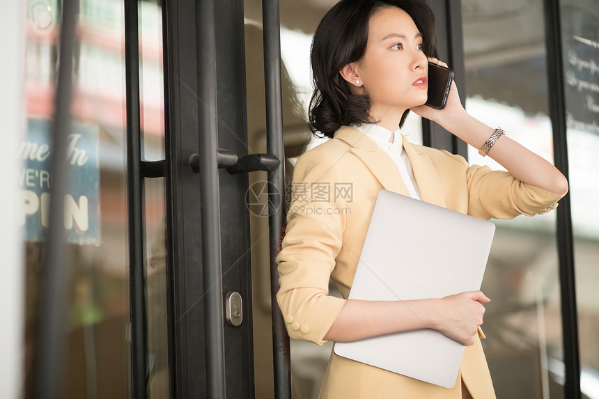 商务女性抱着笔记本电脑打电话