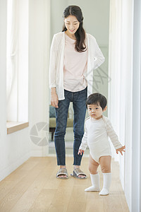 走廊陪着孩子练习走路的母亲图片