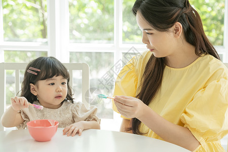 照顾女儿喂饭的母亲背景图片