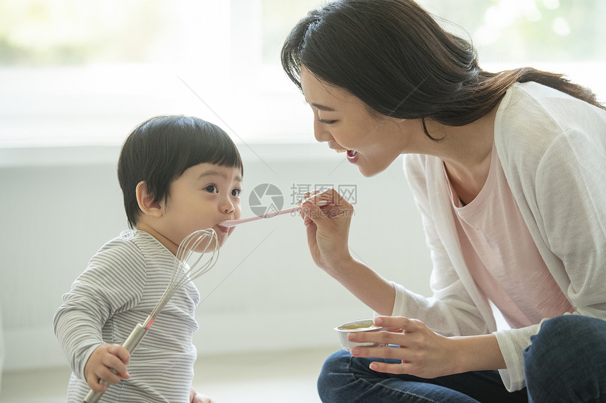 妈妈陪小朋友坐在客厅地毯上吃饭图片