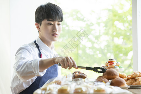 面包店工作夹面包的青年男子背景图片