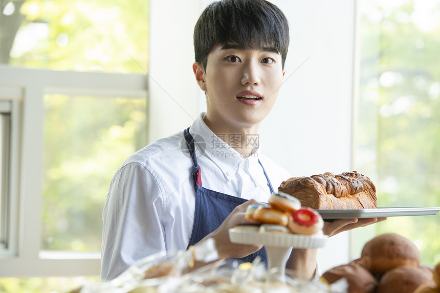 面包店工作端着面包的青年男子图片