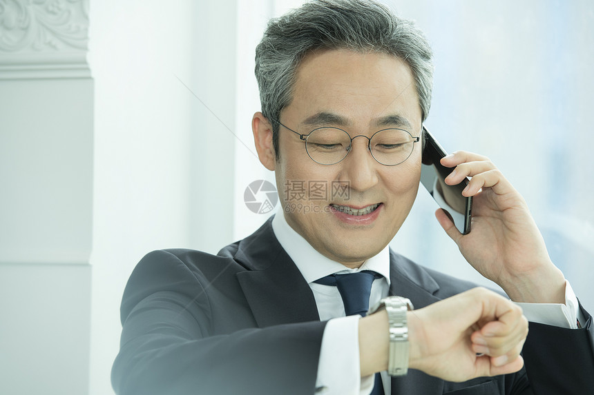 接听电话看手表的商务男性图片