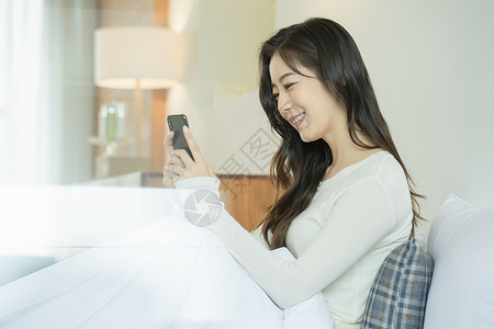 坐在床上玩手机的青年女子高清图片