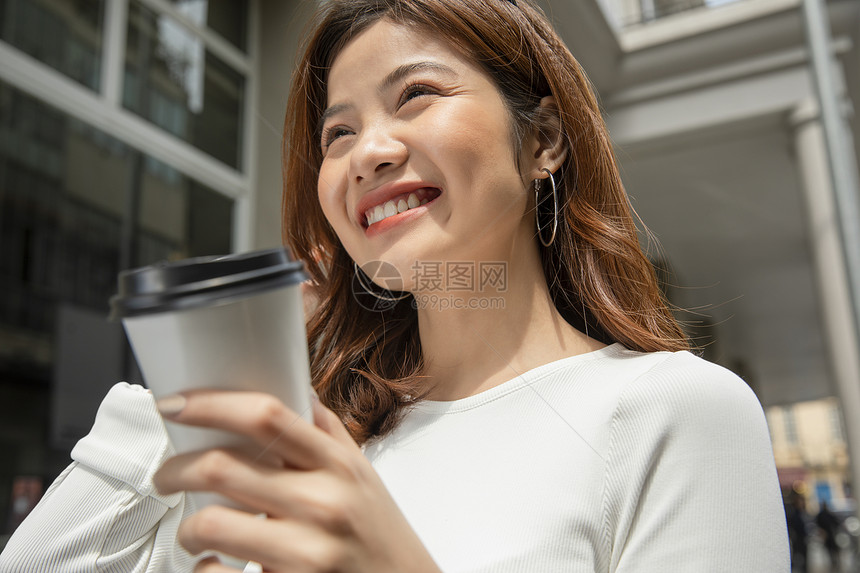 拿着咖啡微笑的青年女子图片