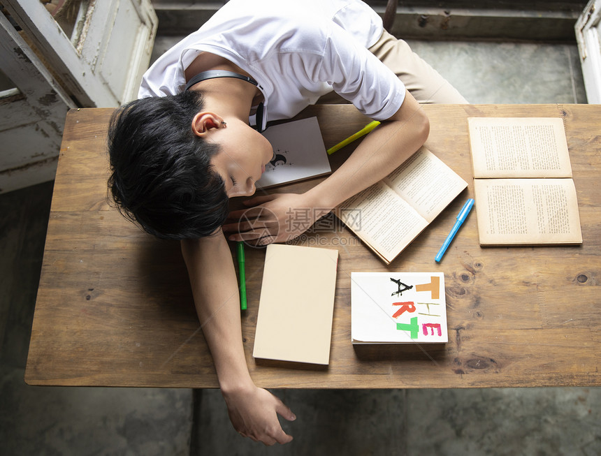 青年男子趴在桌上睡觉图片