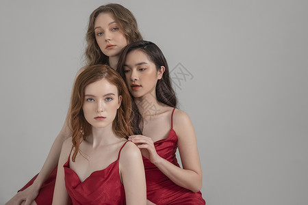 红色晚礼服身着红色长裙拍写真的三姐妹背景