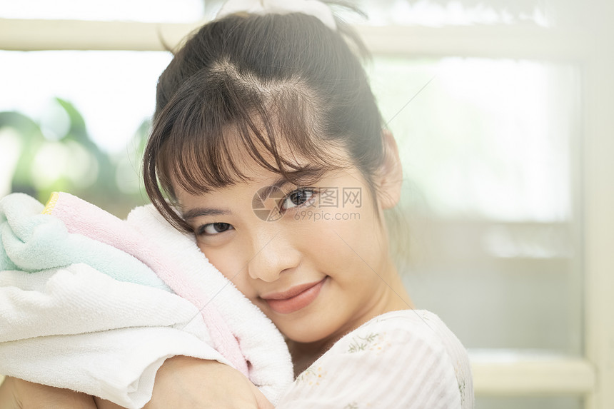 抱着毛巾微笑的年轻女子图片