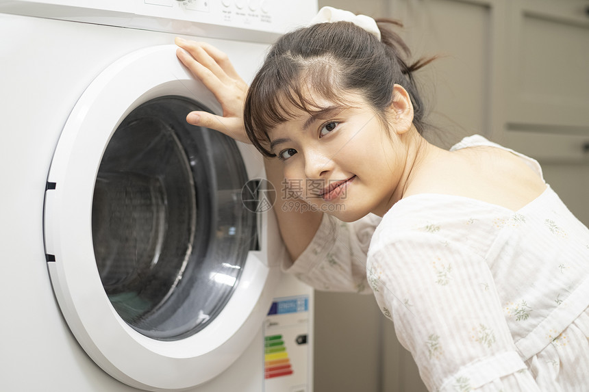 使用洗衣机的年轻女子图片