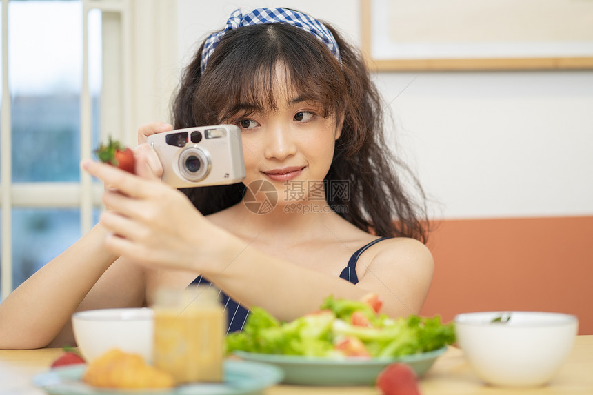 手拿相机拍美食的可爱女孩图片