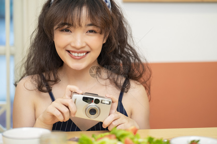 手拿相机拍美食的可爱女孩图片