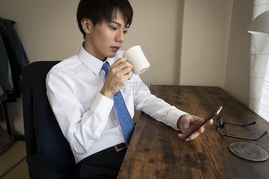 看着手机喝咖啡的商务男青年图片