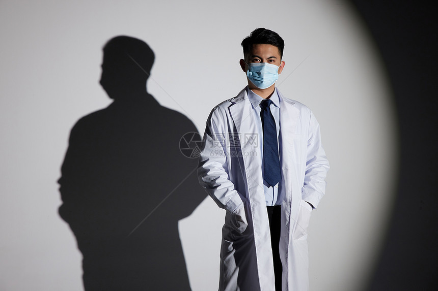 聚光灯下戴口罩的男性医生图片