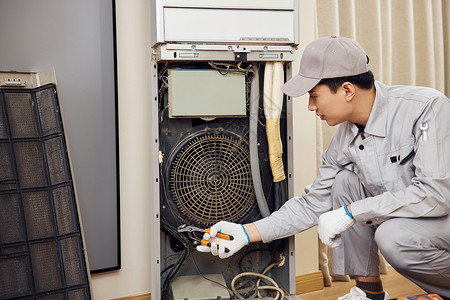 男性维修工人拆卸立式空调机图片素材