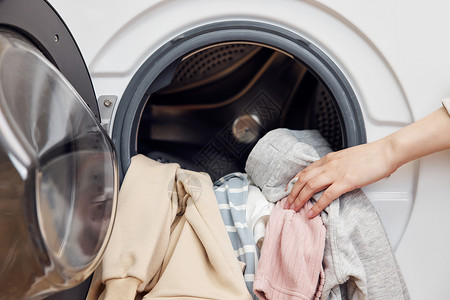 洗衣机电器主图把脏衣物放进滚筒洗衣机特写背景