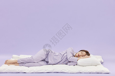 睡觉创意身着睡衣的年轻少女躺在被子上睡觉背景