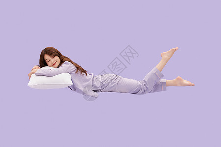 年轻少女趴在枕头上悬浮在空中睡觉高清图片