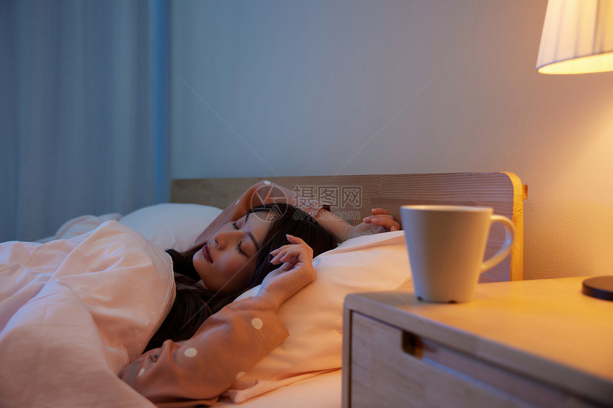 居家女性卧室睡觉和床头柜上的水杯图片
