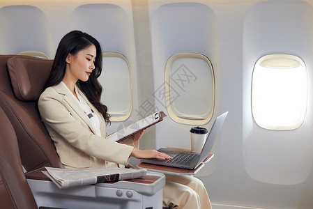 电脑座椅飞机商务舱内休闲办公的商务女士背景