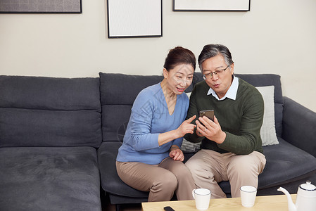 老人使用手机在家使用智能手机打视频电话的老年夫妻背景