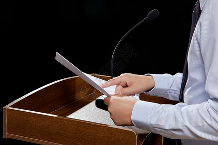 燕尾服讲台上拿着演讲稿发言的商务男士特写背景