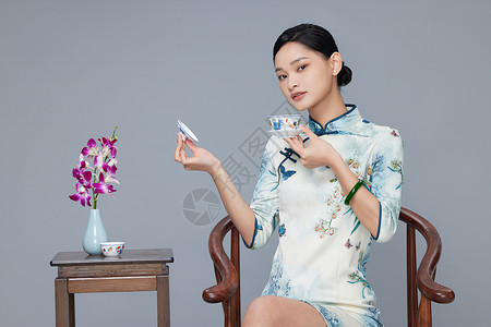 年轻旗袍女性端坐品茶图片