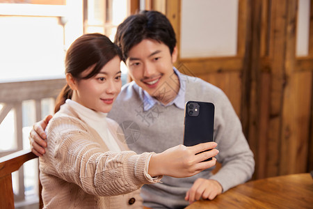 在火锅店拿手机自拍的夫妻相伴高清图片素材