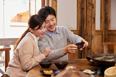 拿手机拍照记录生活的恩爱夫妻吃火锅高清图片素材