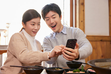 火锅店拿手机抢红包的情侣情人节高清图片素材