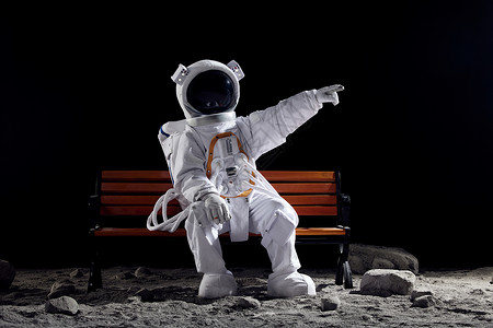 创意宇航员坐在长椅上手指前方背景图片