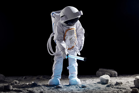 宇航员手持探照设备站在月球表面上背景图片