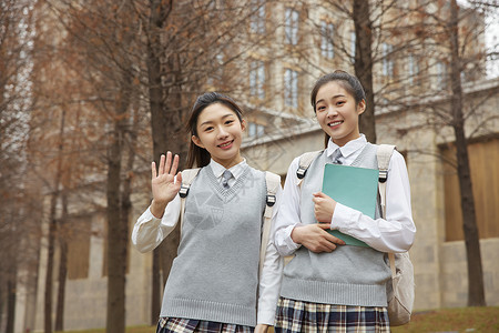 校园美女学生抱着书本打招呼图片素材