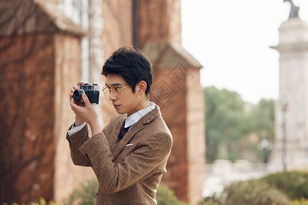 户外使用老式照相机拍照的男青年高清图片