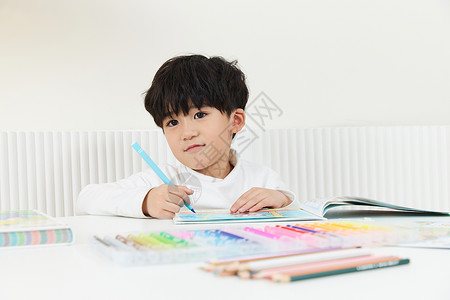 坐在桌前开心画画的小男孩图片
